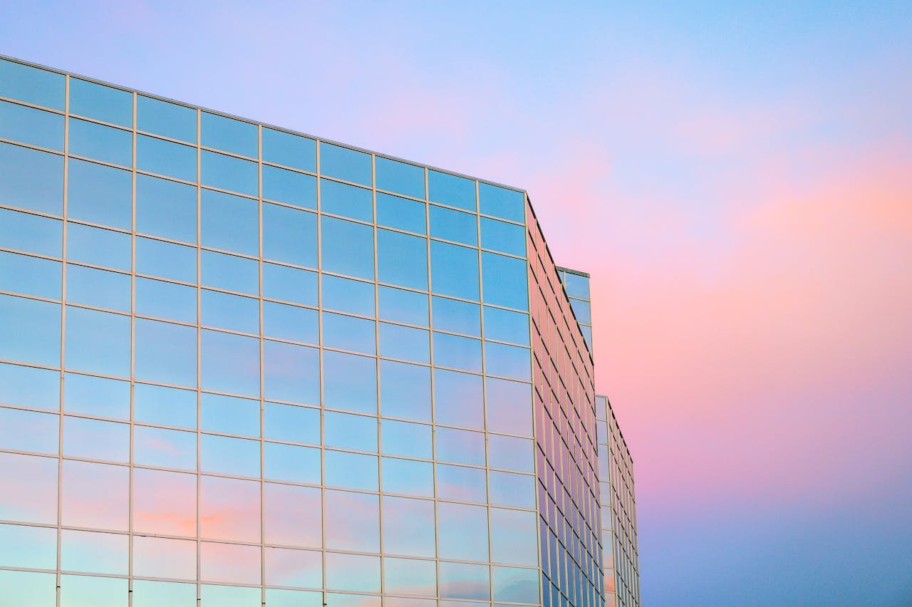 Exterior of contemporary building with glass mirrored walls located in city against colorful sky at sunrise time